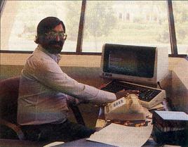 Shiraz Shivji seated at his desk beside a computer terminal in his Atari office